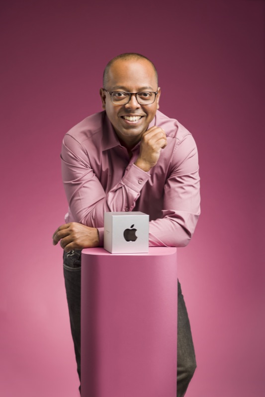 Bijoy Thangaraj posing with the Apple Design Award against a pink background